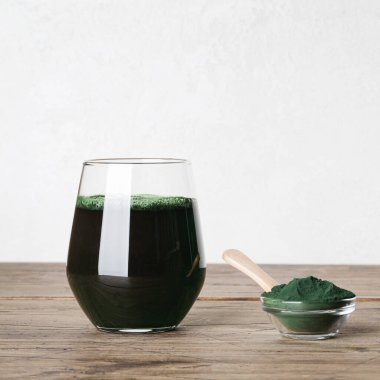 Taze yeşil içecek, camda spirulina, ahşap zemin üzerinde kaşık olan spirulina tozu. kullanışlı alışkanlıklar