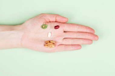 Sağlıklı yemek. Yeşil arka planda fasulye ve fındık formunun üst görüntüsü. Vegan çiğ diyet konsepti. Boşluğu kopyala