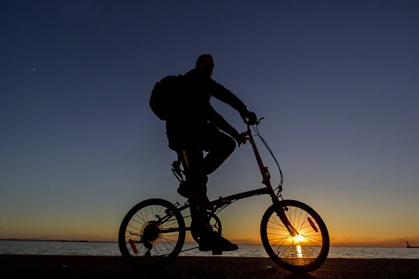 Силует велосипедиста, який їде на шосейному велосипеді на заході сонця — стокове фото