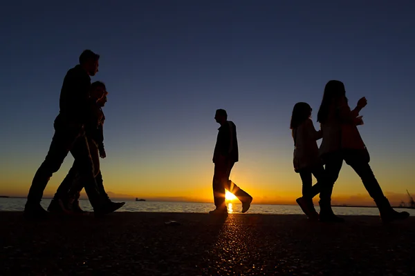 Silhouetten von Menschen, die auf dem Sonnenuntergang gehen — Stockfoto