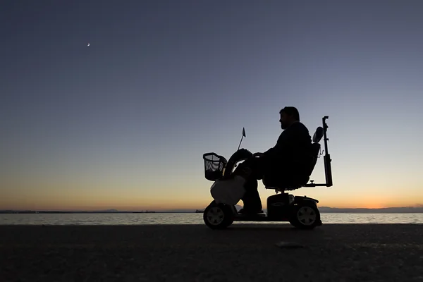 Silueta de una persona con discapacidad en silla de ruedas en su —  Fotos de Stock