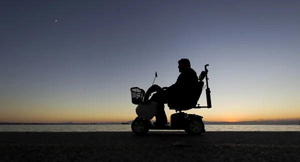 Silueta de una persona con discapacidad en silla de ruedas en su — Foto de Stock