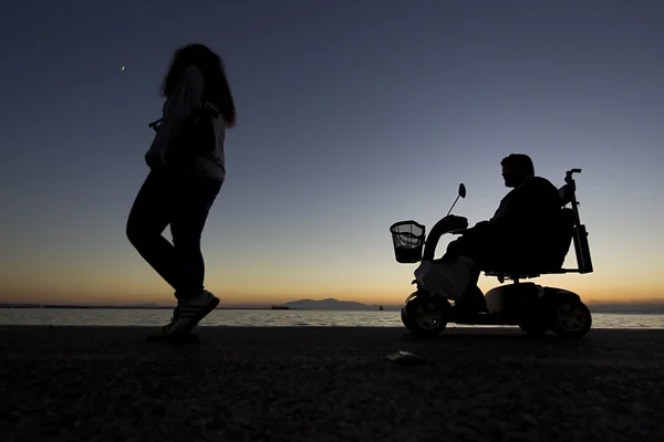 Silhouette eines Menschen mit Behinderungen im Rollstuhl auf der Straße — Stockfoto