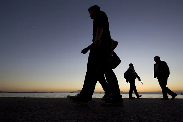 Silouètes de personnes marchant sur le coucher du soleil — Photo