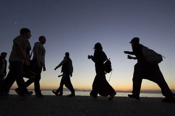 Silouetes de pessoas que caminham no pôr do sol — Fotografia de Stock