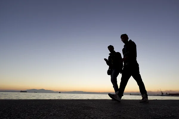 Silouetes de pessoas que caminham no pôr do sol — Fotografia de Stock