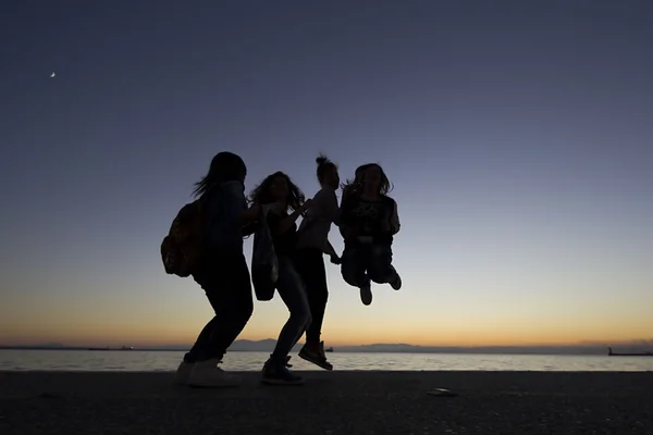 Silouetes de pessoas que caminham no pôr do sol — Fotografia de Stock