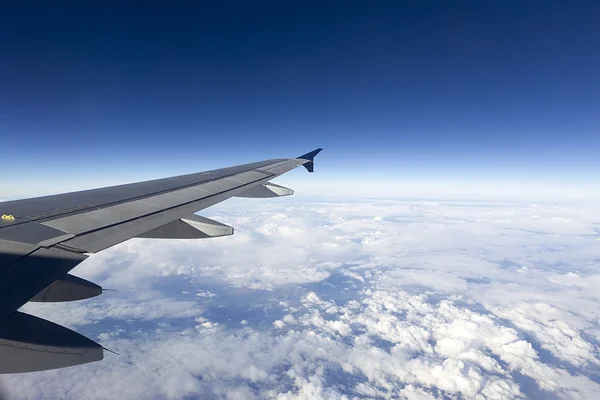 Wing of airplane flying above the clouds in the sky — Stock Photo, Image