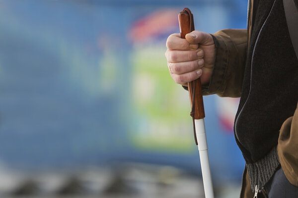 Close up in blind man's hands holding a stick