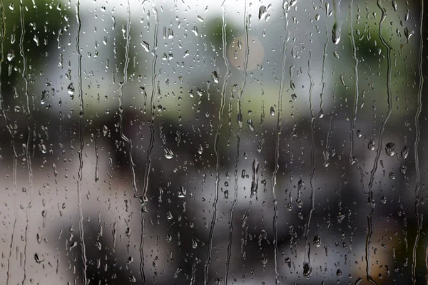 Lluvia cae sobre la ventana con un fondo — Foto de Stock