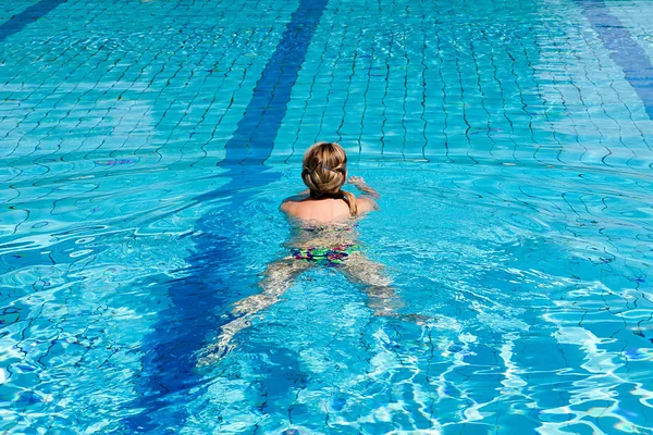 Jovem com maiô nadando em uma piscina de água azul — Fotografia de Stock