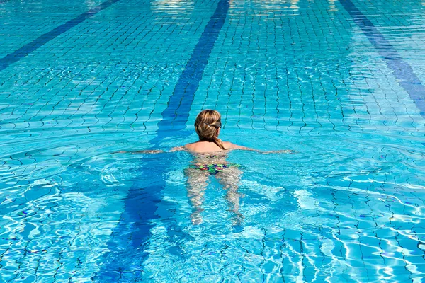 Fiatal nő, fürdőruha úszás egy kék vizű medence — Stock Fotó