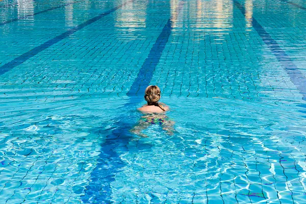 Молодая женщина в купальнике плавает в голубом бассейне — стоковое фото