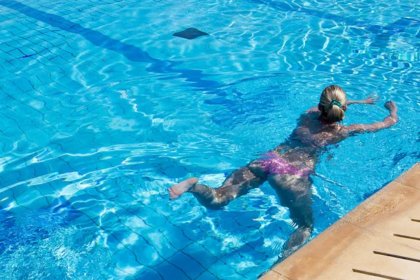 Jovem com maiô nadando em uma piscina de água azul — Fotografia de Stock