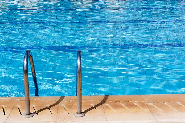 Piscina com escada e reflexos ensolarados — Fotografia de Stock