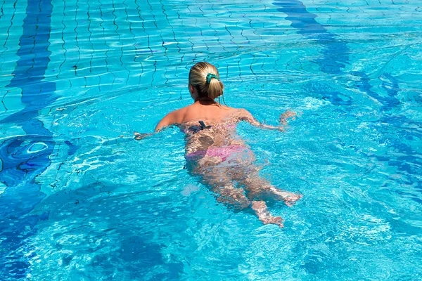 Jovem com maiô nadando em uma piscina de água azul — Fotografia de Stock