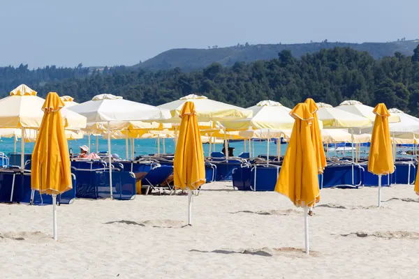 Sombrillas cerradas en la playa con tumbonas y sombrillas en la —  Fotos de Stock
