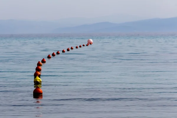 Fila boa rossa galleggiante in mare blu in linea . — Foto Stock