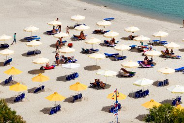 Beach with tourists, sun beds and umbrellas. Expected to be the  clipart