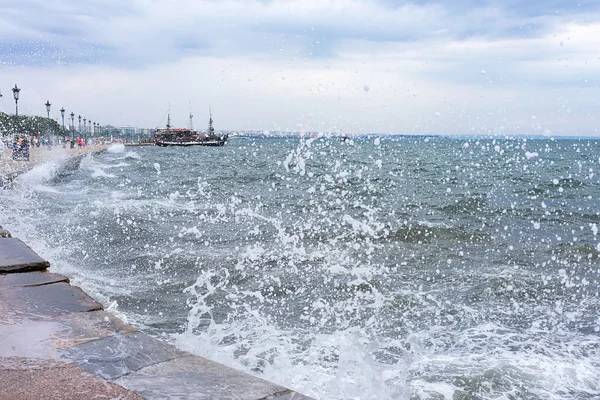 Forsande surfa på en våg slå mot hamnen i thessaloniki, — Stockfoto