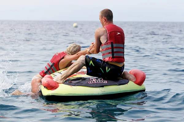 Unrecognized man helping woman to get on water inflatable. 20 mi — Stock Photo, Image