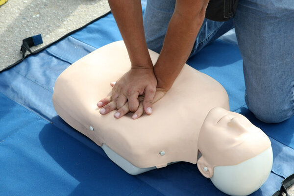 Male instructor showing CPR on training doll