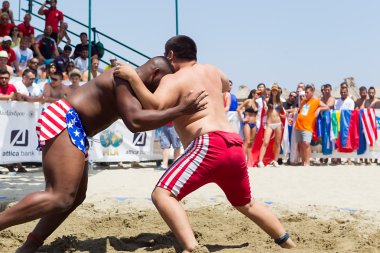 Two male athletes wrestle on sand during the First World Champio clipart