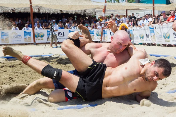 Deux athlètes masculins luttent sur le sable pendant le premier champion du monde — Photo