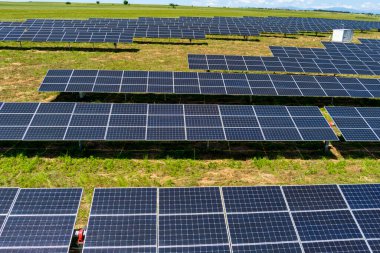 Hava manzaralı fotovoltaik paneller Yunanistan 'ın kuzeyinde yeşil alana park ediyorlar. Mavi gökyüzü güneş panellerine yansıyor. Geleceğin alternatif enerji santrali. Sürdürülebilir enerji kaynağı. Yenilenebilir elektrik teknolojisi