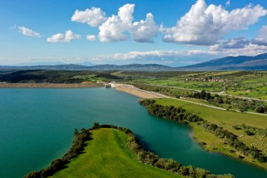 Pinios Gölü 'nün havadan görünüşü. Yunanistan 'ın Mora bölgesindeki Ilia' daki Pinios nehrinde inşa edilen baraj sonrasında yapay bir göl oluşturuldu. Yeşil tepeli yüksek manzaralı su manzarası, güneşli yaz günlerinde dağlar.