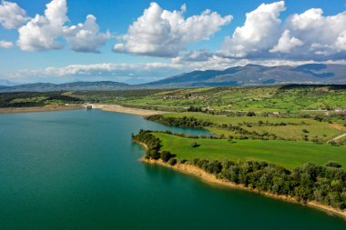 Pinios Gölü 'nün havadan görünüşü. Yunanistan 'ın Mora bölgesindeki Ilia' daki Pinios nehrinde inşa edilen baraj sonrasında yapay bir göl oluşturuldu. Yeşil tepeli yüksek manzaralı su manzarası, güneşli yaz günlerinde dağlar.