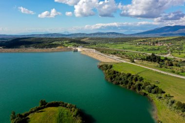 Pinios Gölü 'nün havadan görünüşü. Yunanistan 'ın Mora bölgesindeki Ilia' daki Pinios nehrinde inşa edilen baraj sonrasında yapay bir göl oluşturuldu. Yeşil tepeli yüksek manzaralı su manzarası, güneşli yaz günlerinde dağlar.