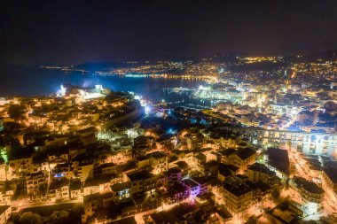 Yunanistan 'ın kuzeyindeki Kavala kenti, antik su kemeri Kamares, evler ve ortaçağ şehir duvarları gece hava manzaralı.