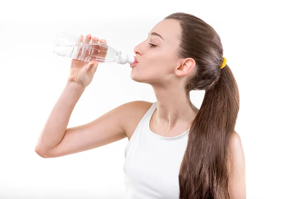 Chica bebiendo agua en el deporte contra un fondo blanco . —  Fotos de Stock