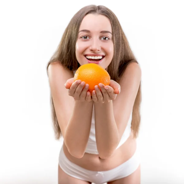 Девушка улыбается и держит оранжевый на белом фоне — стоковое фото
