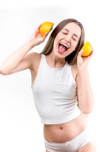 Beyaz zemin üzerine portakal ile kulaklıklar ile şarkı söyleyen kız — Stok fotoğraf