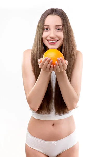 Chica sosteniendo naranja y sonriendo — Foto de Stock