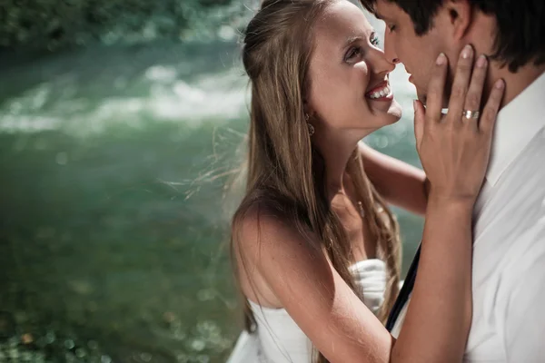 Schönes Hochzeitspaar umarmt und lächelt auf dem Fluss — Stockfoto