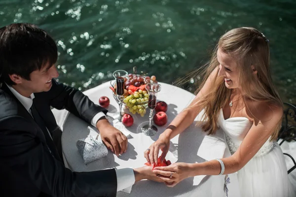 Hochzeitspaar sitzt am geschmückten Tisch und umarmt sich — Stockfoto