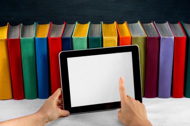 arka plan üzerinde renkli kitaplar ile tablet okuma
