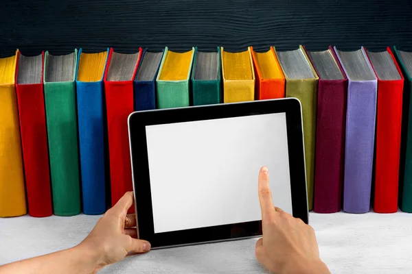 Reading on the tablet with colorful books on background — Stock Photo, Image