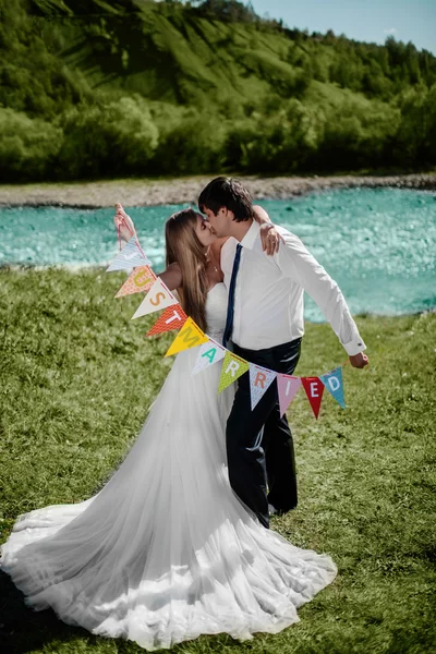 Lächelndes Hochzeitspaar mit "frisch verheirateten" Fahnen — Stockfoto