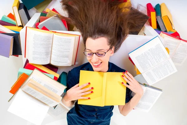 Jonge en slim meisje liggen met boek omgeven door kleurrijke boek — Stockfoto