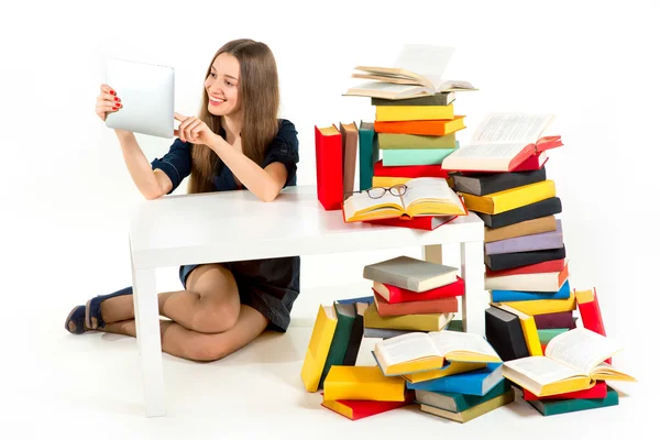 Flickan läsa något på tavlan med massor av onödiga böcker — Stockfoto