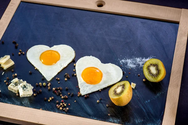 Breakfast with eggs, cheese, kiwi and orange juice on chalkboard — Stock Photo, Image