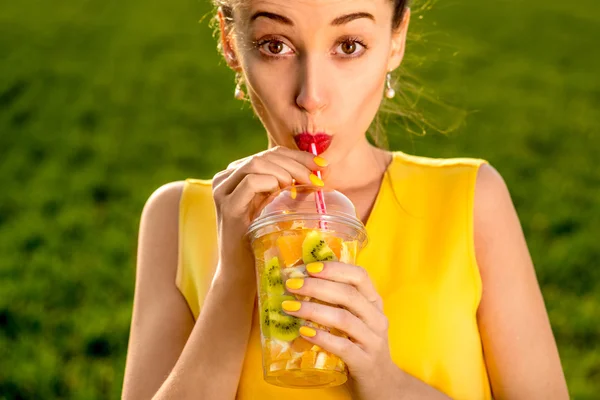 Jeune femme buvant des fruits de la tasse transparente sur gr vert — Photo