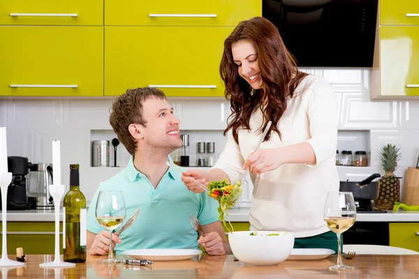 Beautiful couple preparing to the dinner with salad and pasta on — Stock Photo, Image