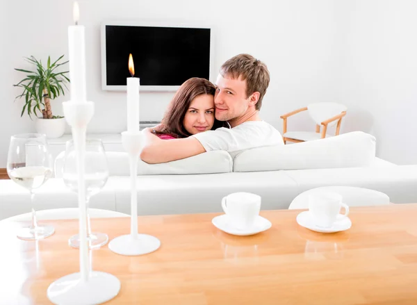 Jovem casal sentado no sofá e assistindo tv no hom — Fotografia de Stock