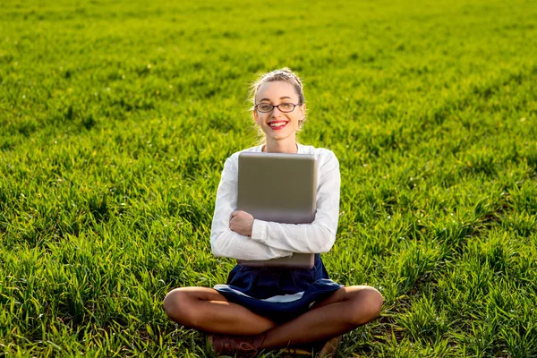 Молодая улыбающаяся женщина, девушка с ноутбуком в зеленом поле или парке — стоковое фото