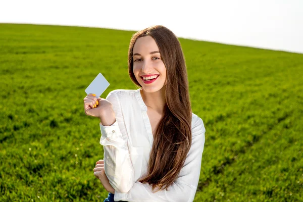 Smiling business woman holding credit card on the green field — Stock Photo, Image